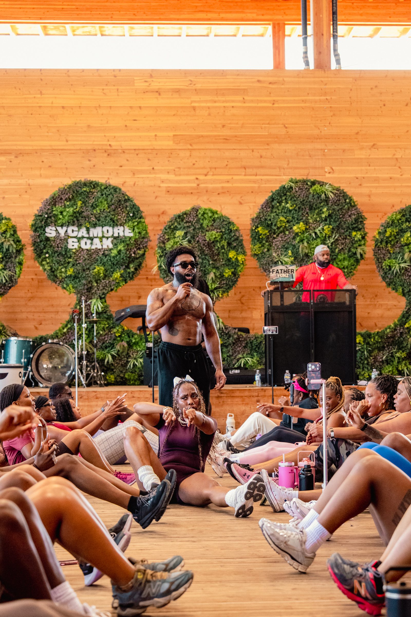 Shirtless instructor teaching on the stage, class seated in a circle