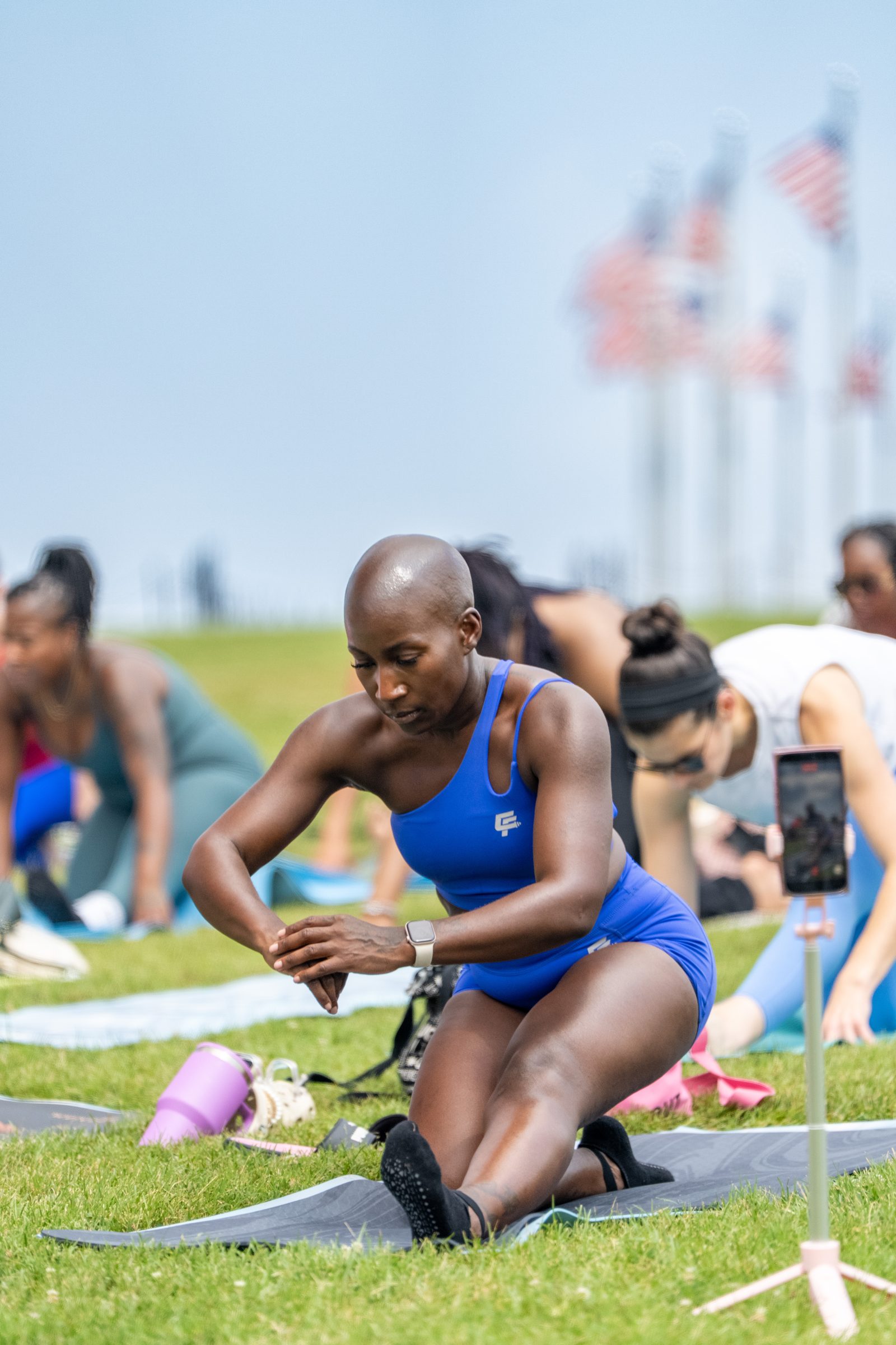 Focused participant in blue mid-squat, class blurred behind