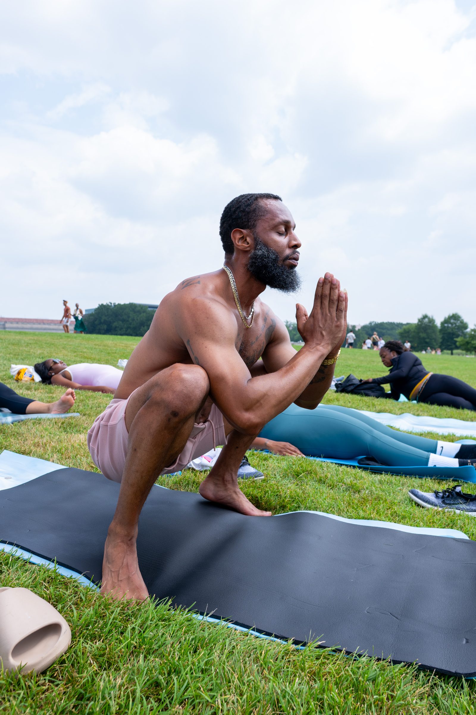 Participant in a low squat, hands in prayer, meditative