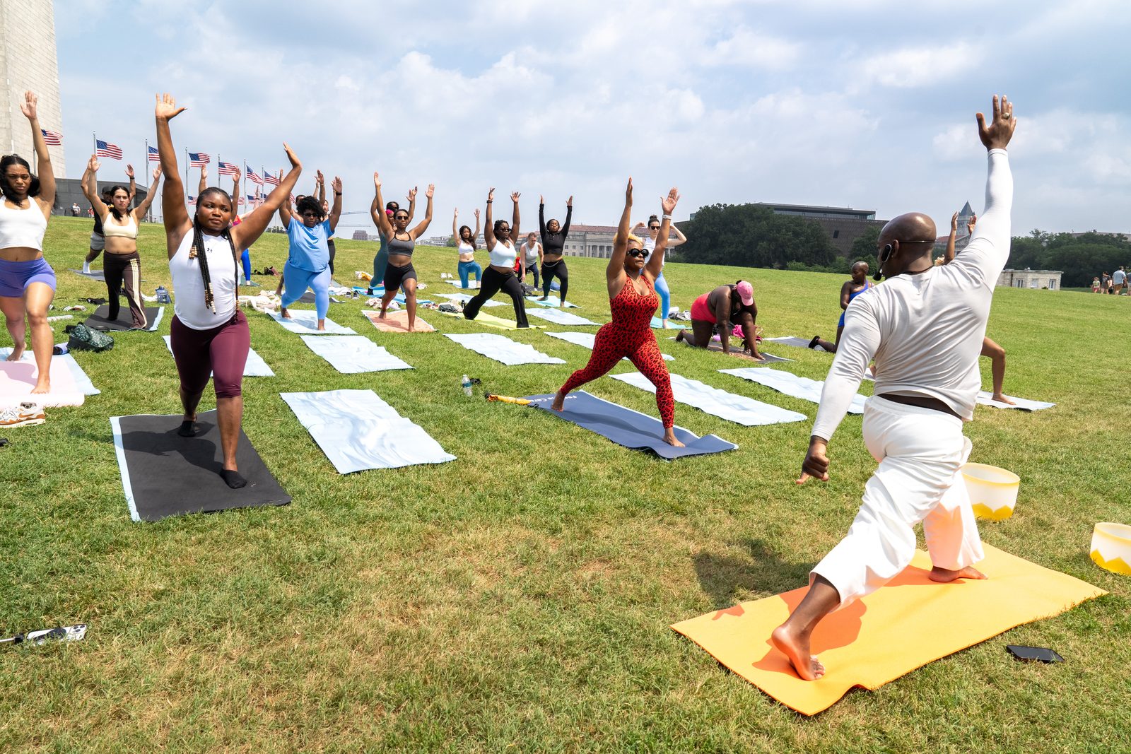 The class in warrior pose, arms raised, instructor leading in the foreground