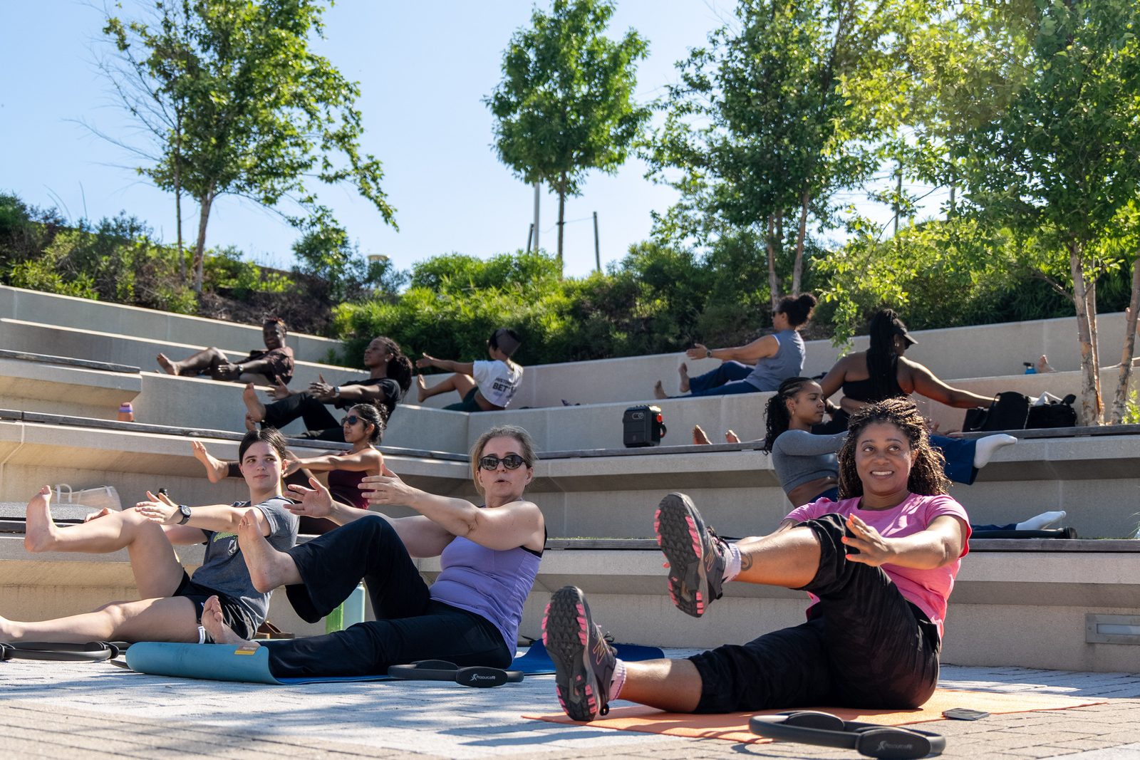 The full class doing seated boat pose across the amphitheater steps