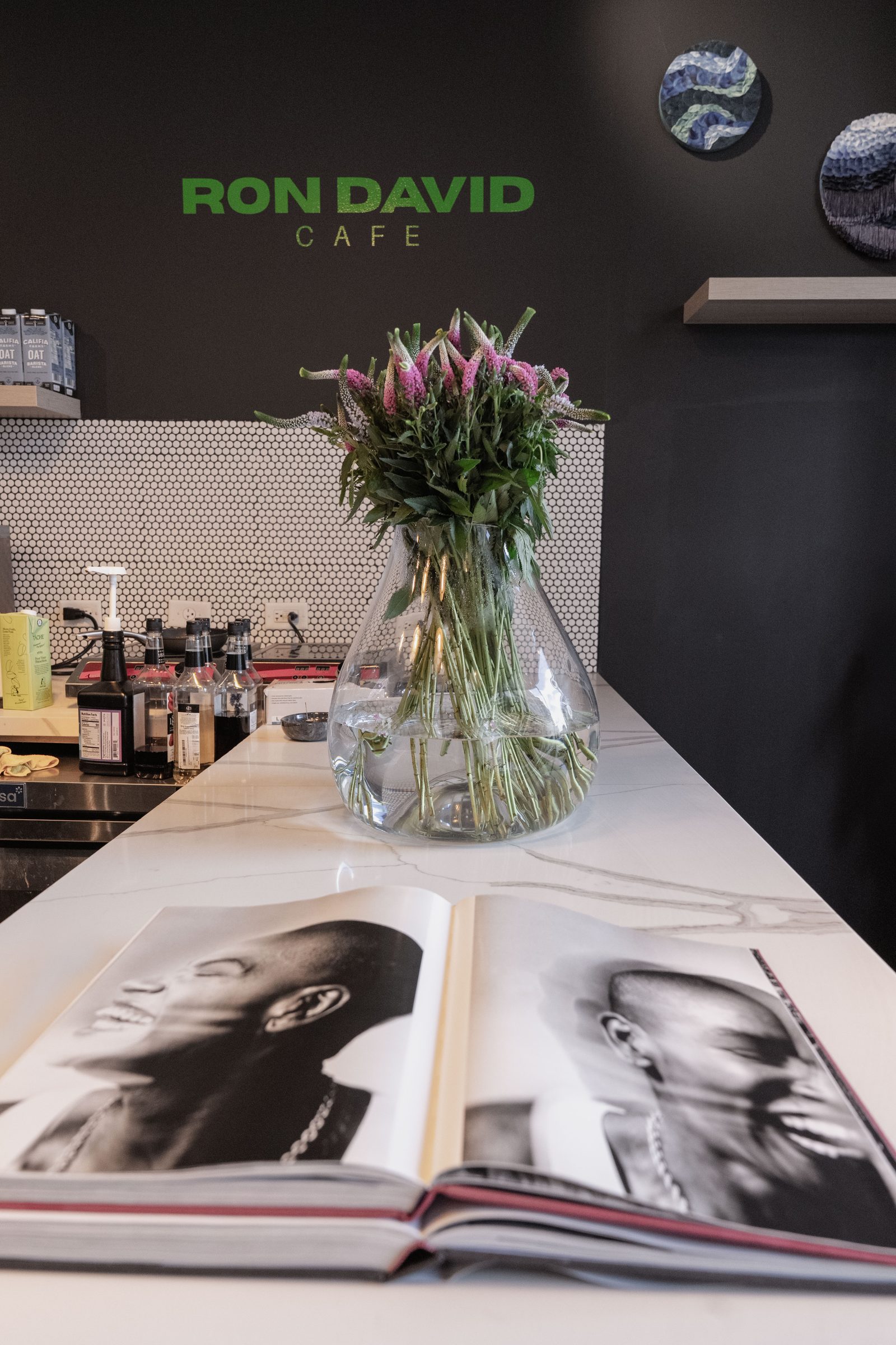Vase of veronica flowers on the marble counter with the Ron David Café signage behind