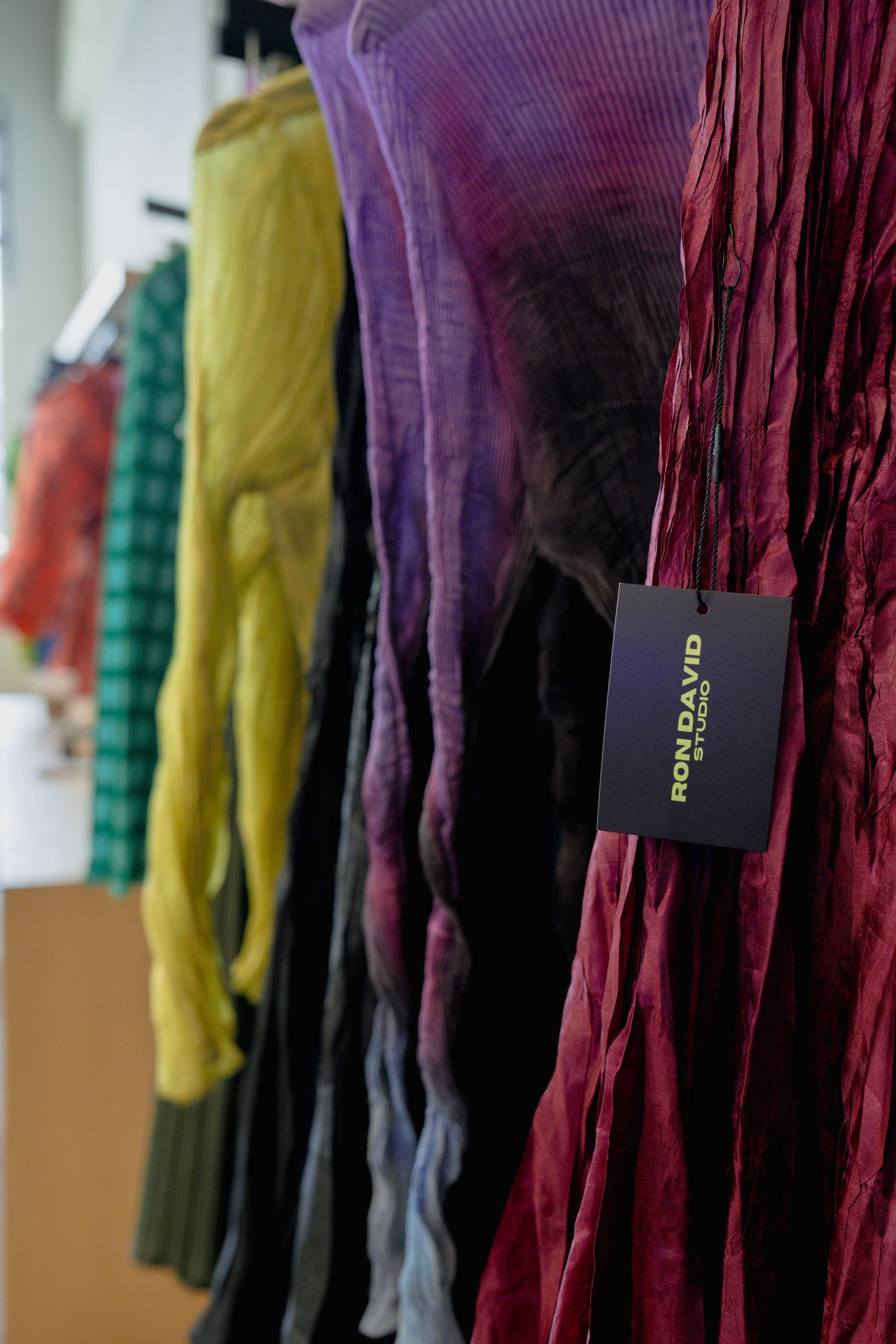 Close-up of a clothing rack in a color gradient from green to yellow to purple to red
