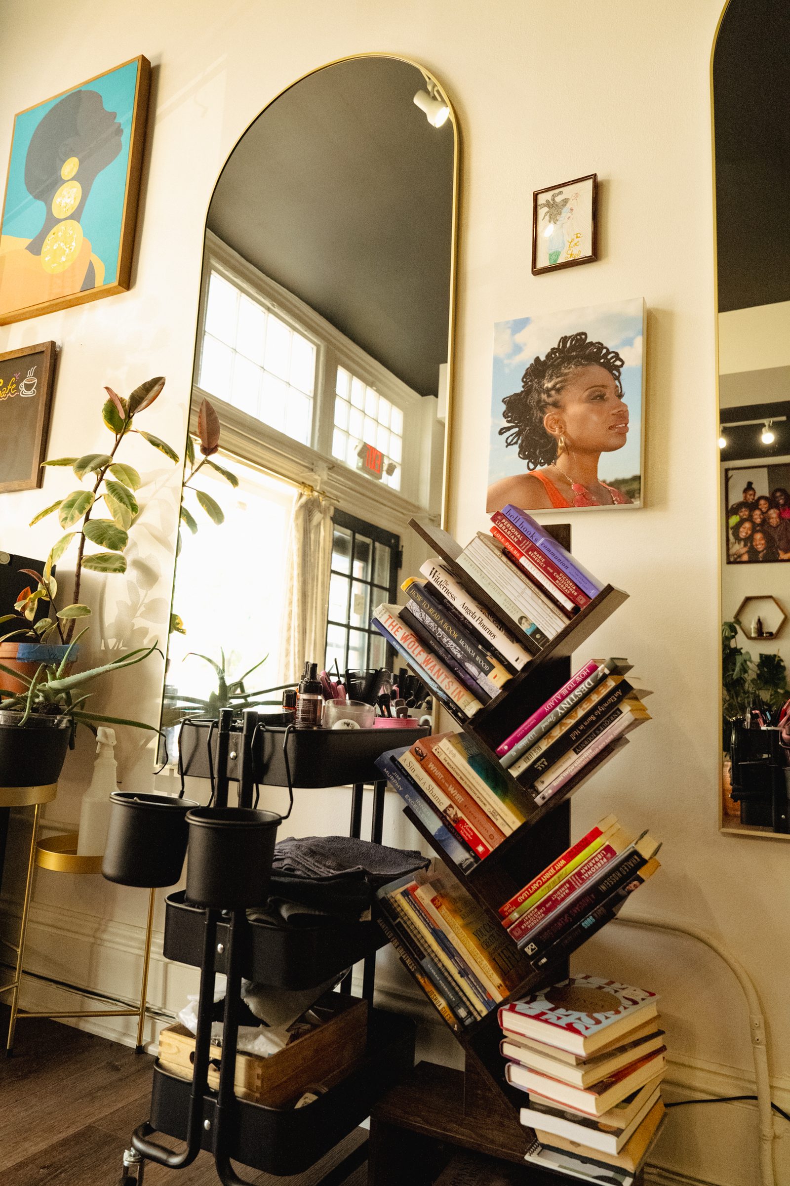 Salon interior: arched mirror, bookshelf full of titles, art on the walls